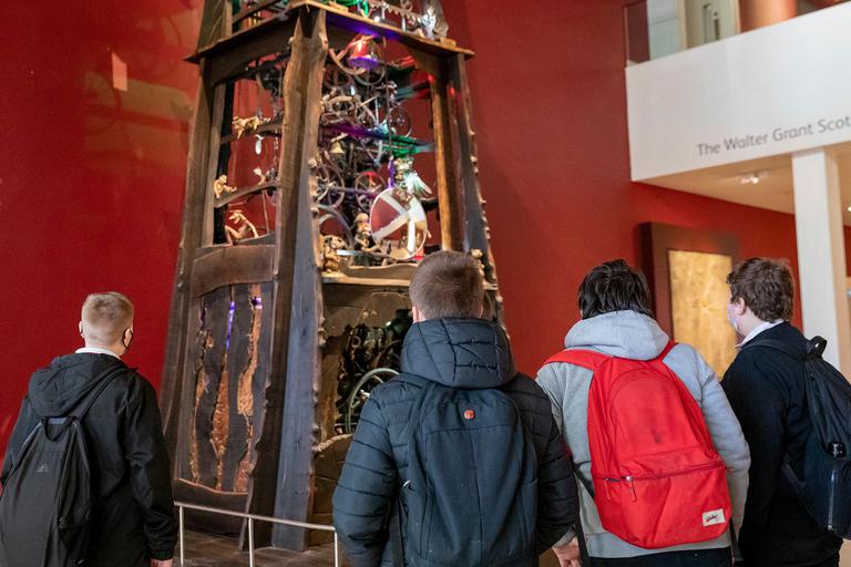 A group of school children looking at the Millenium Clock in the Collecting Stories gallery.